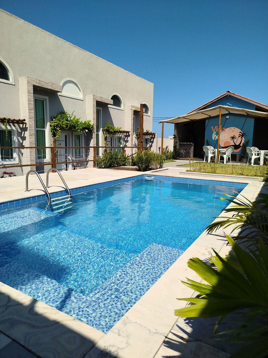 Piscina azul-turquesa do Vida Bela Lofts em dia de sol, cercada pelos lofts e pelo quiosque de palha